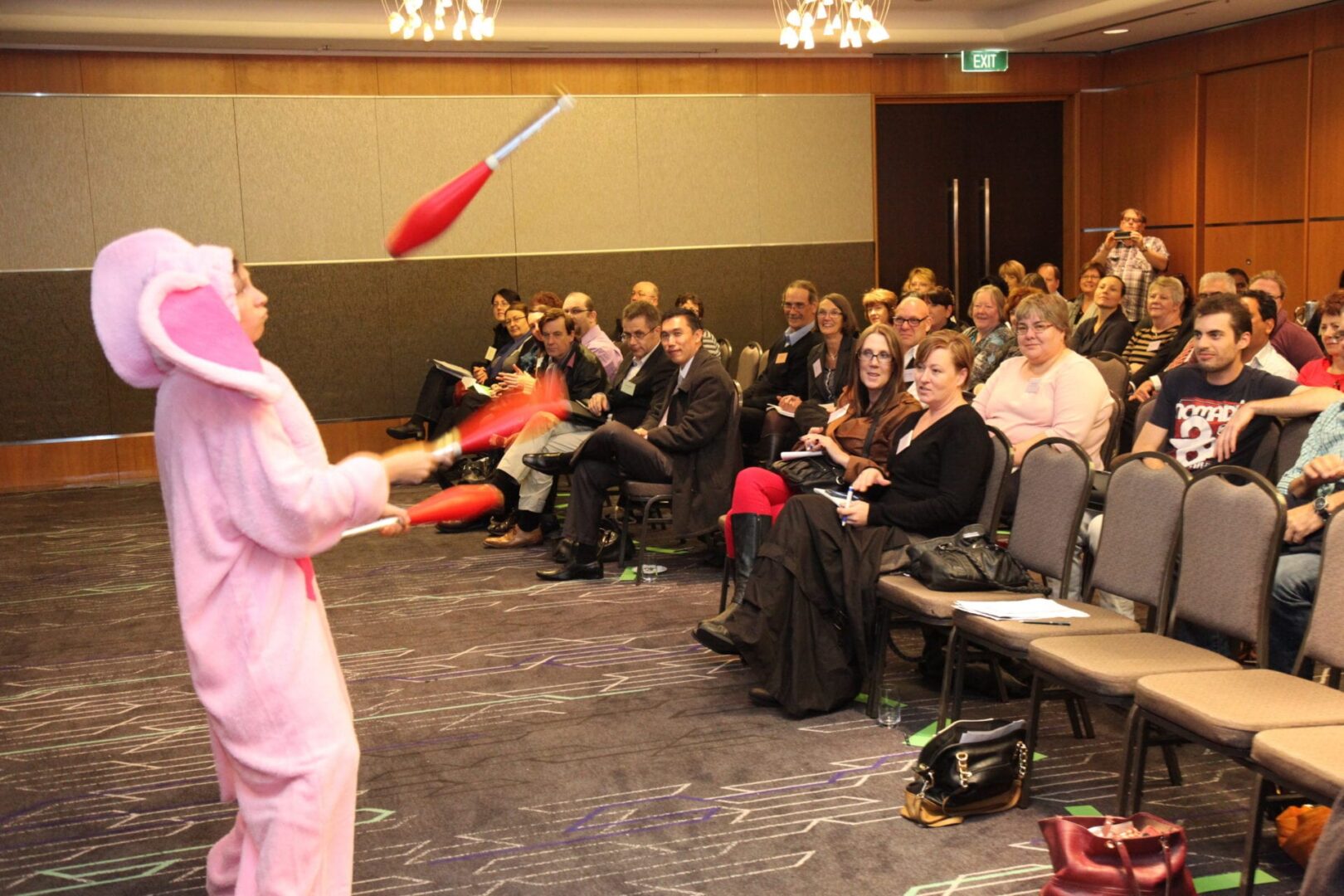 A man in pink is juggling red objects