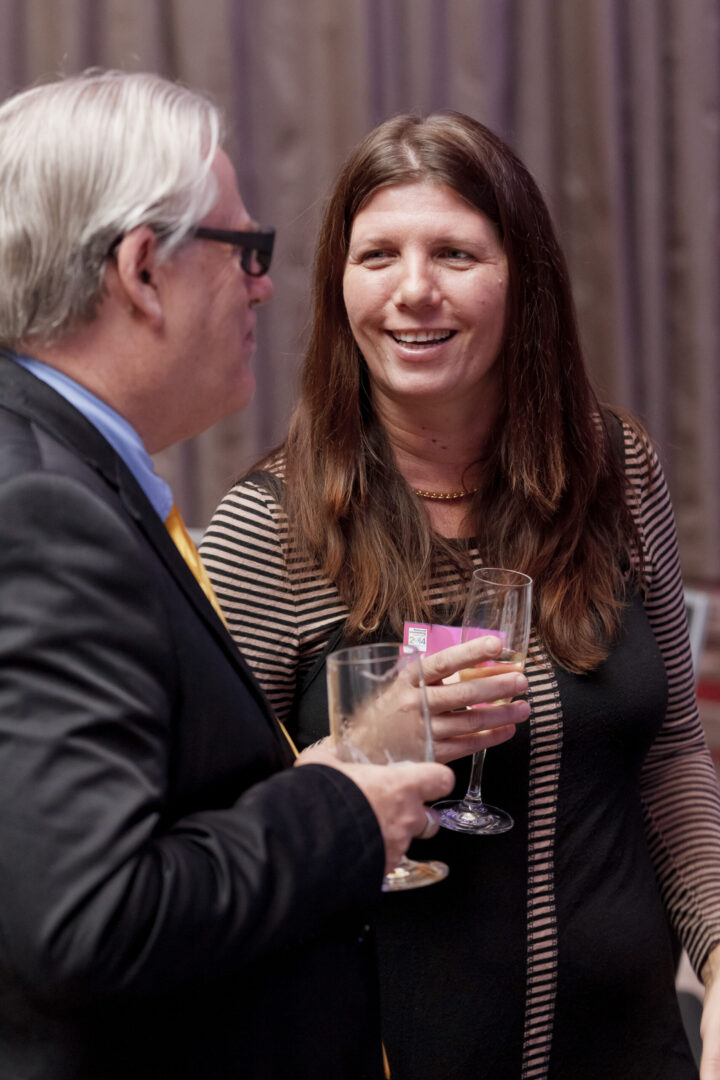 A man and woman are drinking wine at an event.