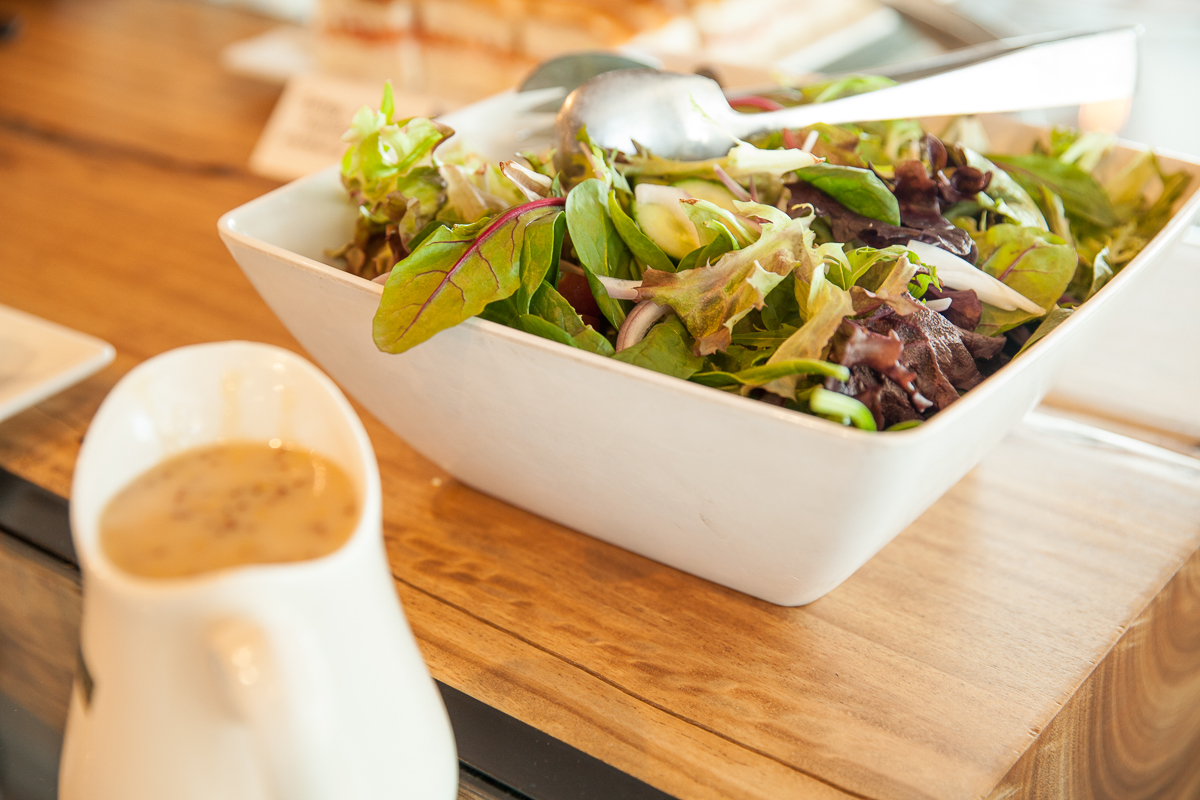 A bowl of salad on top of a wooden table.